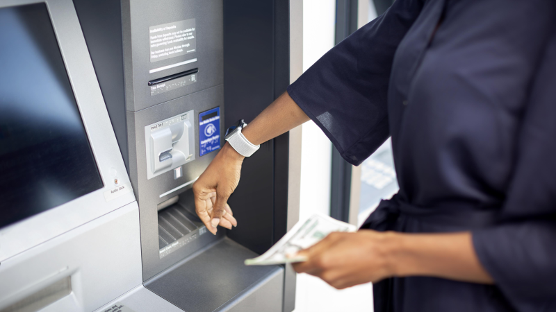 Woman using her smartwatch during Contactless transaction at ATM to deposit money. 